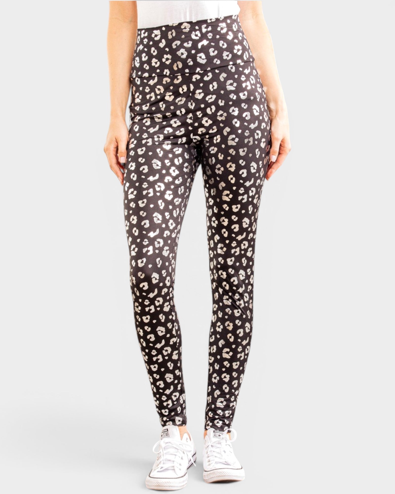 Person wearing black leggings with a white leopard print pattern on a white background