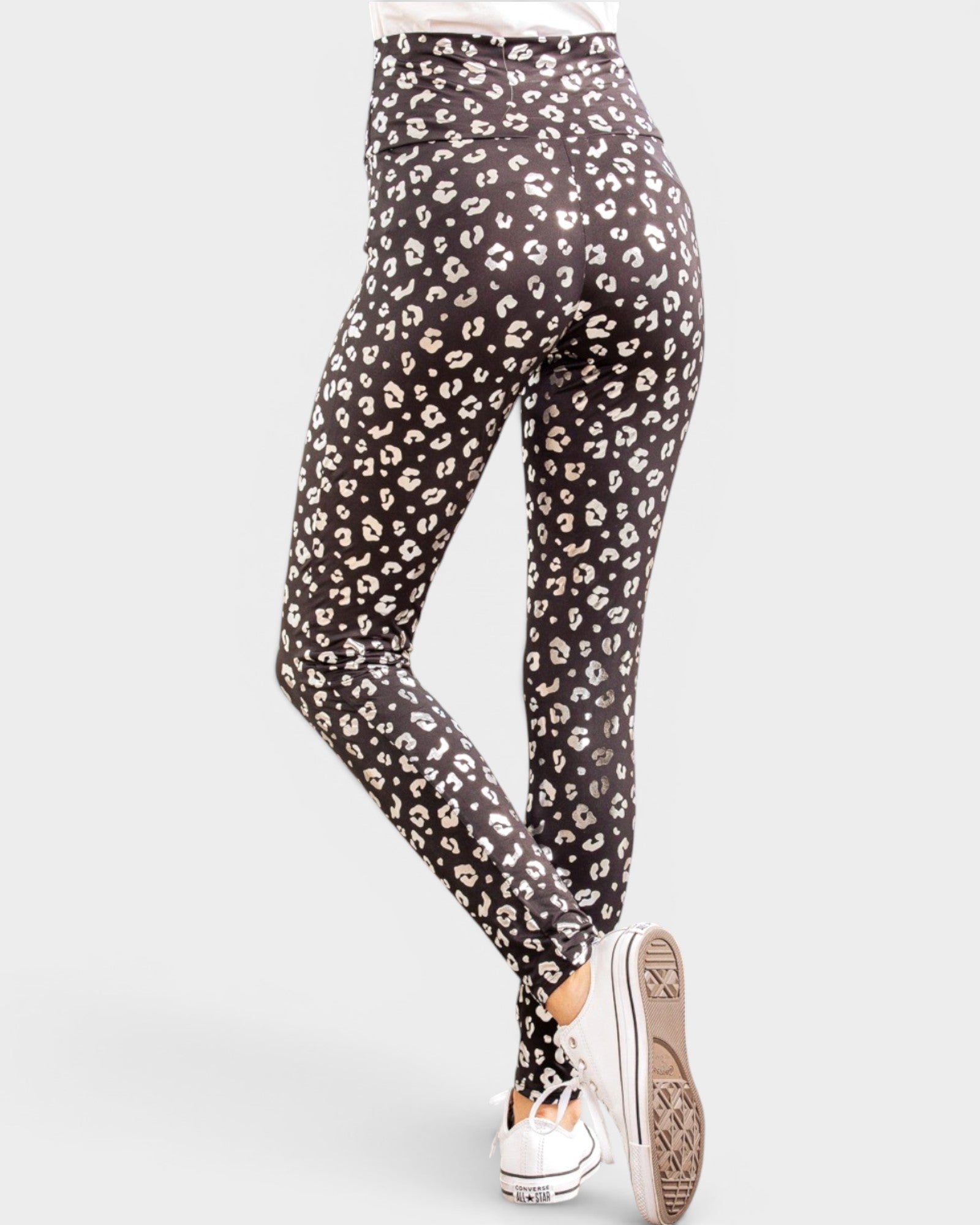 Black leggings with a white leopard print pattern worn by a person on a white background