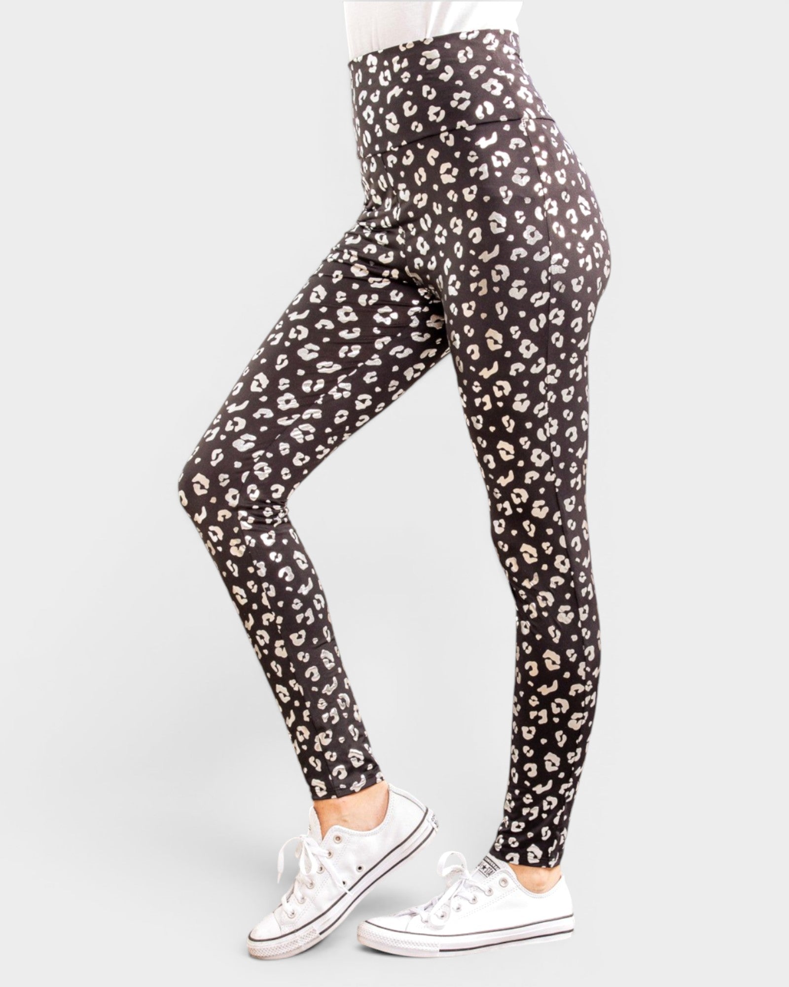Person wearing black leggings with white leopard print pattern on a white background