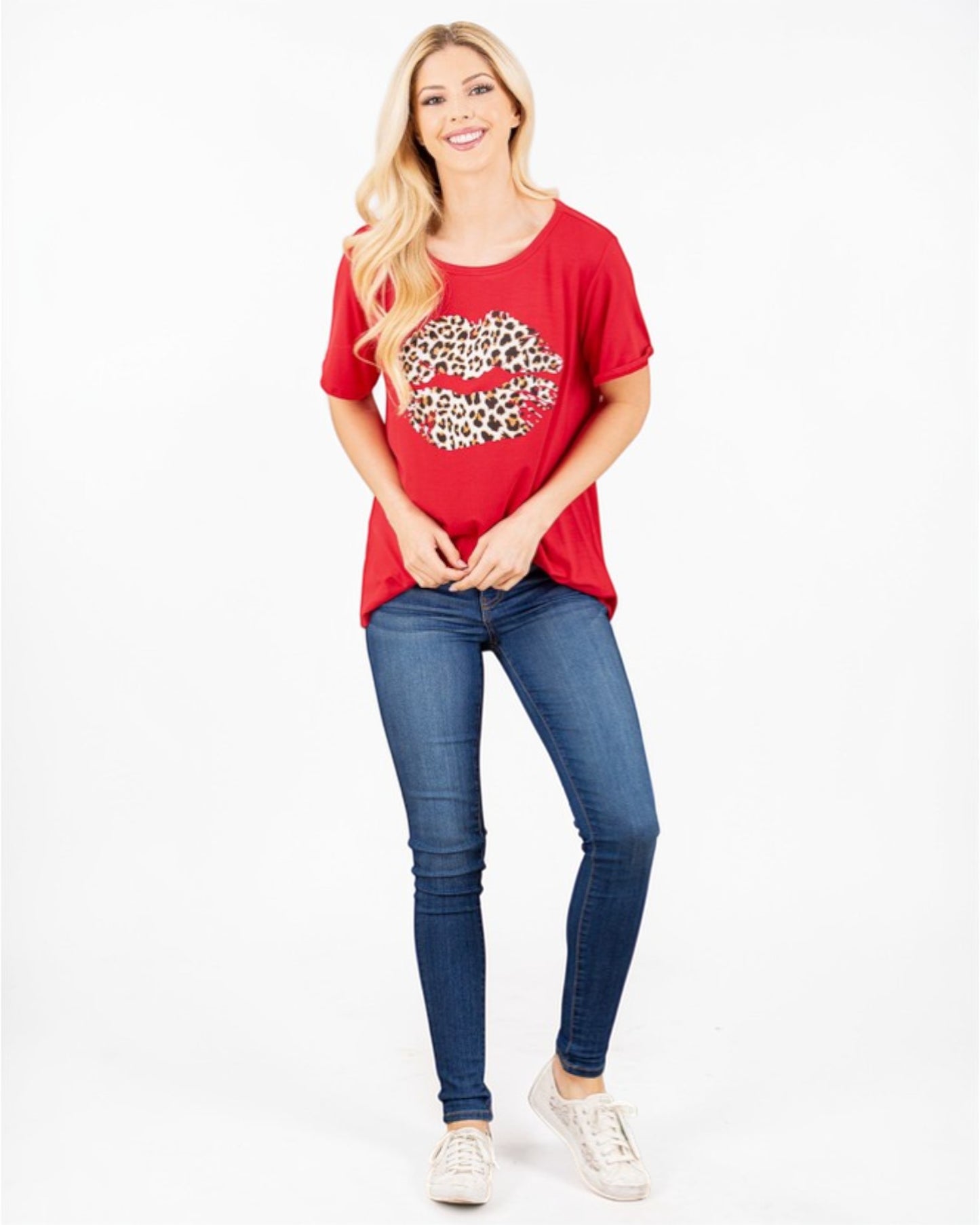 Woman wearing a red t-shirt with a leopard print heart design and blue jeans on a white background