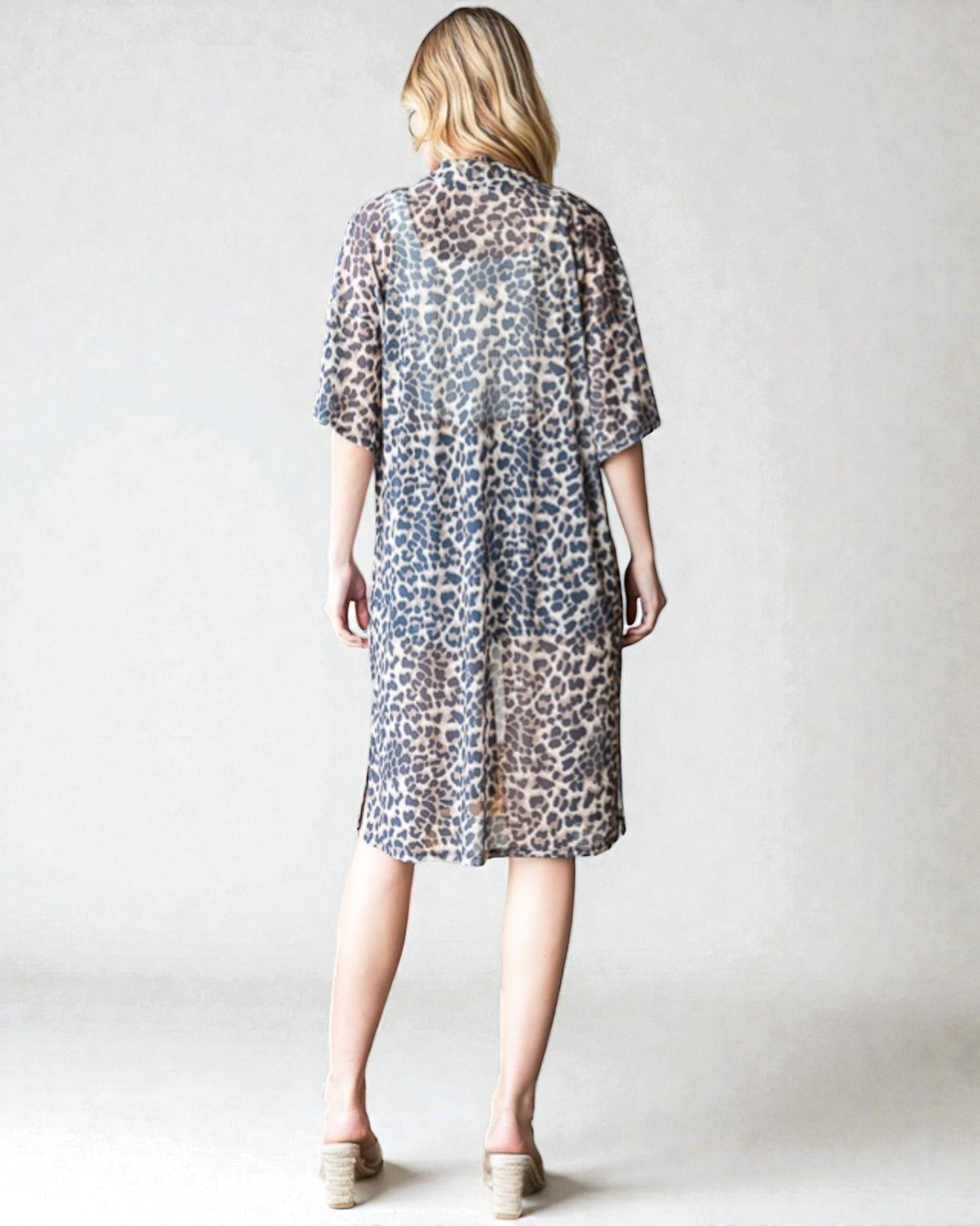 Woman wearing a leopard print dress against a plain background