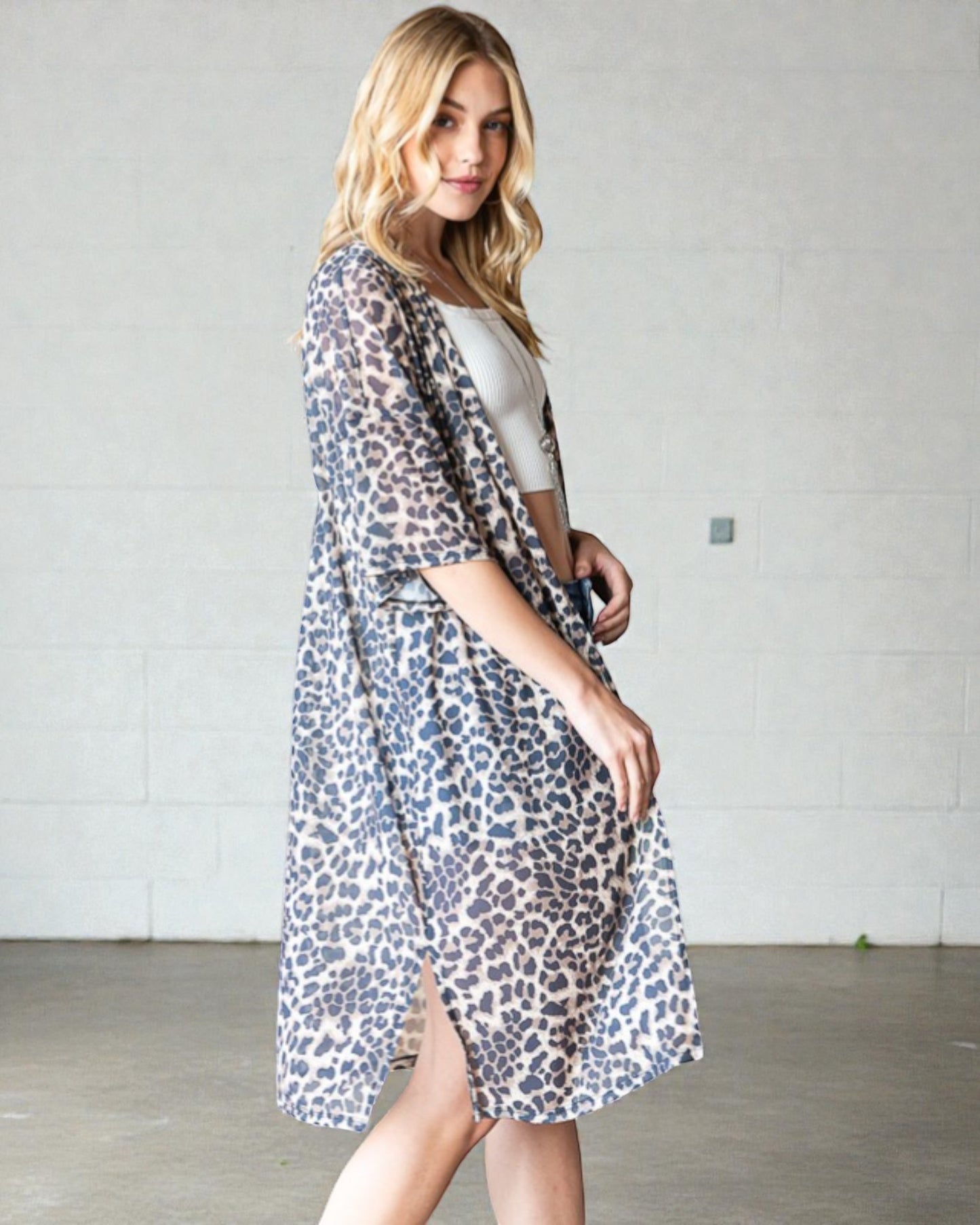 Woman wearing a leopard print kimono over a white shirt against a plain background