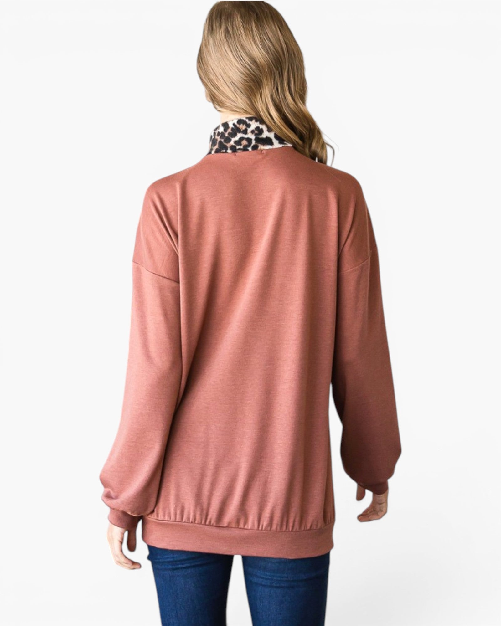 A woman shown from the back wearing a dusty rose long-sleeve knit top with a leopard-print collar, paired with blue jeans, against a plain white background.