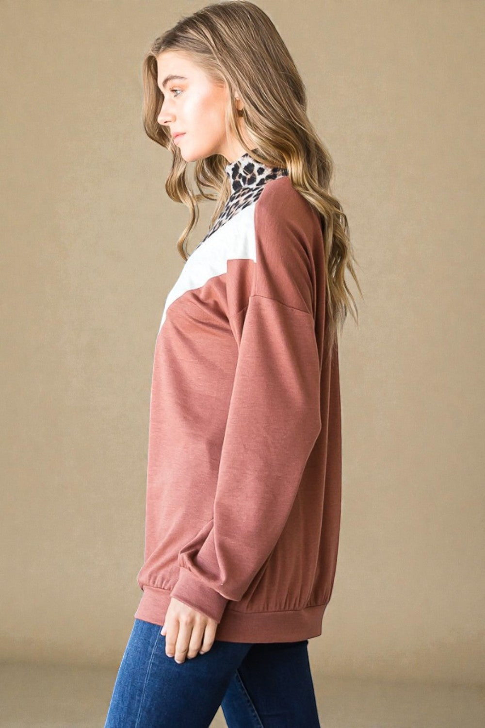 Woman wearing a brown and white color-blocked sweater against a beige background