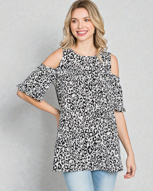 Woman wearing a leopard print cold shoulder top against a gray background