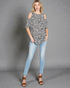 Woman wearing a leopard print top and light blue jeans against a gray background