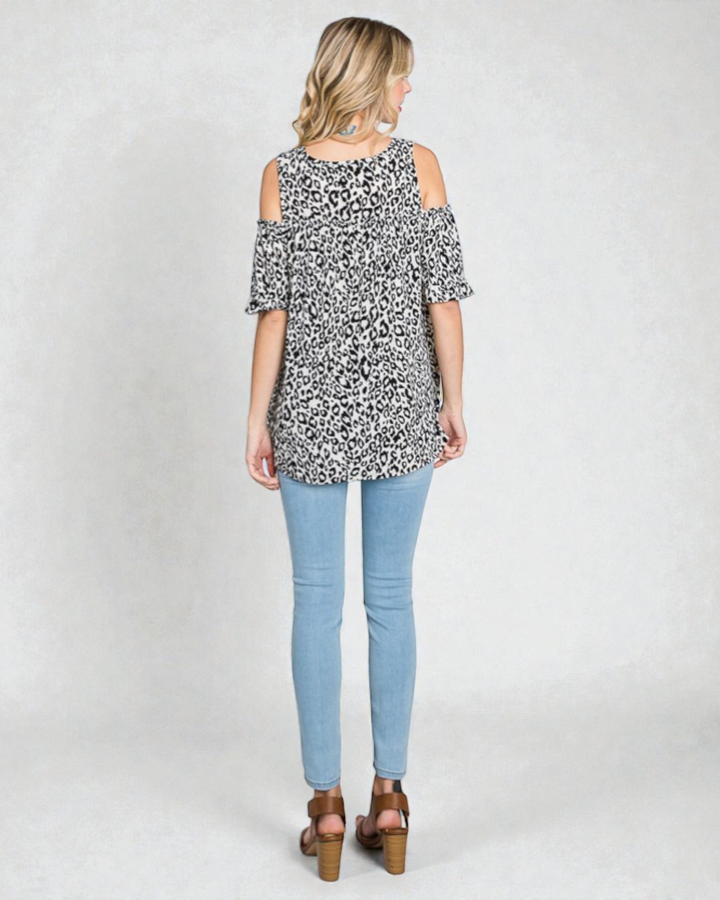Woman wearing a leopard print top and light blue jeans on a white background