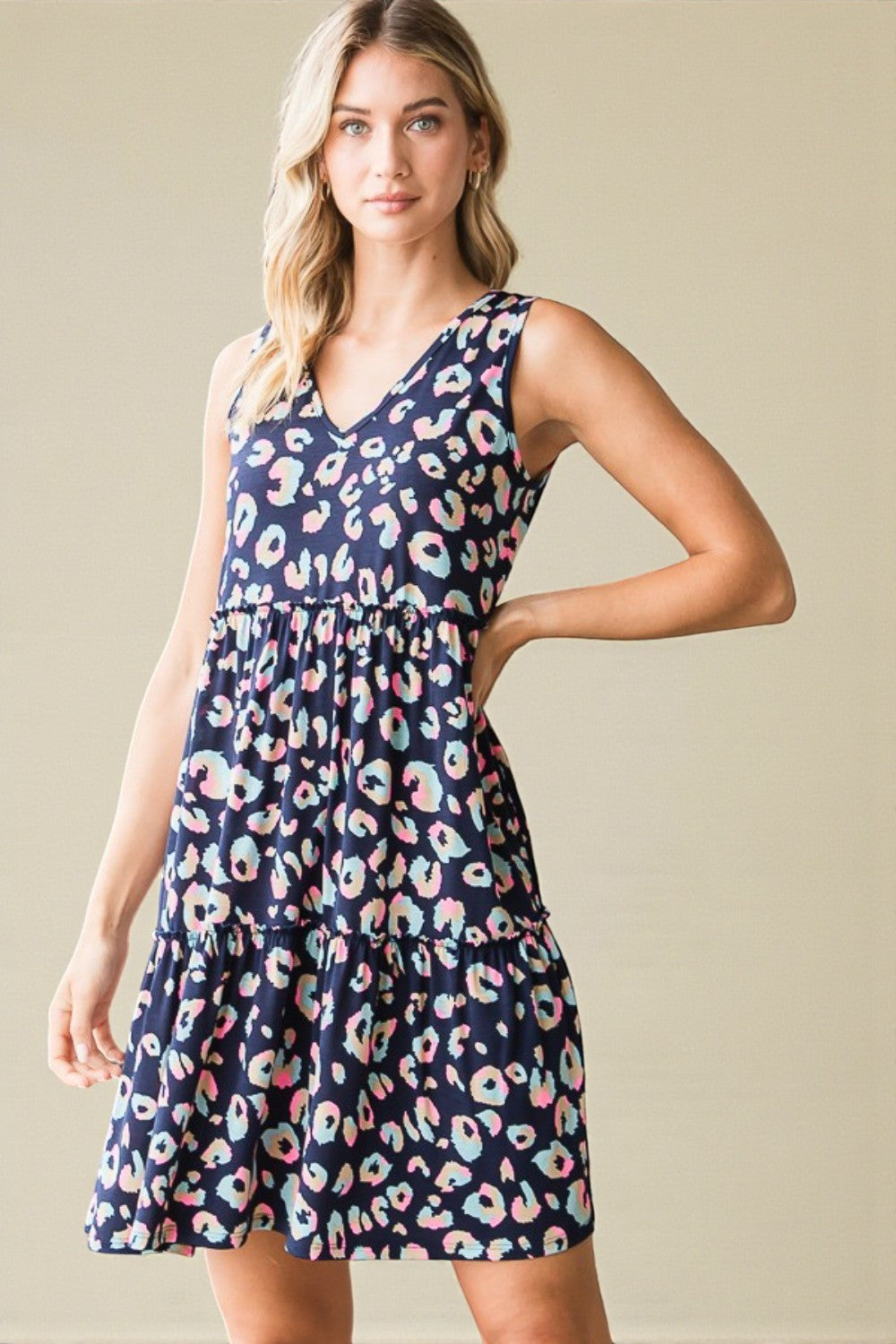 Woman wearing a navy dress with colorful floral pattern against a beige background