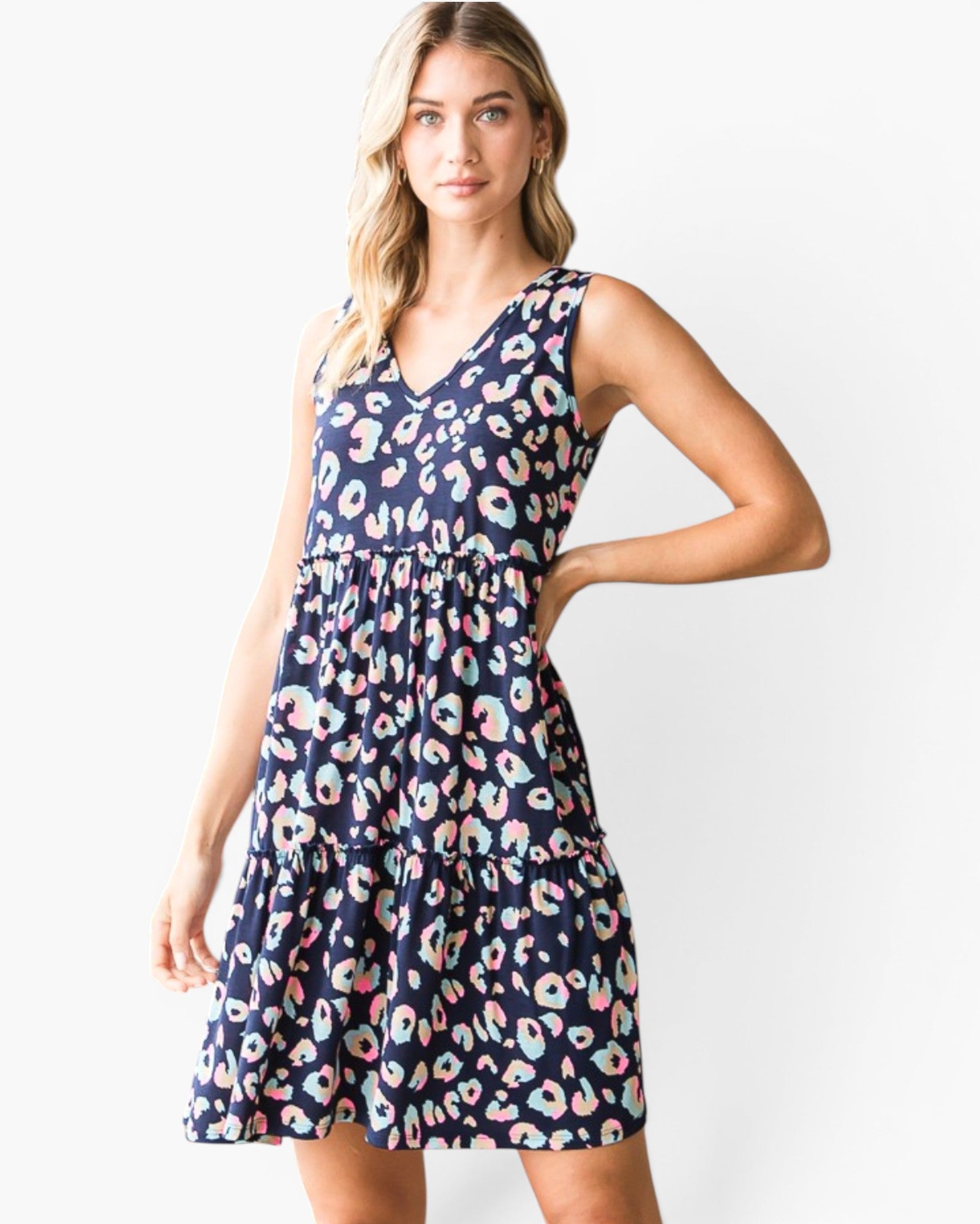 A woman modeling a sleeveless V-neck tiered dress with a navy blue background and a colorful donut print, set against a plain white studio background.