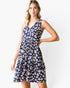 A woman modeling a sleeveless V-neck tiered dress with a navy blue background and a colorful donut print, set against a plain white studio background.