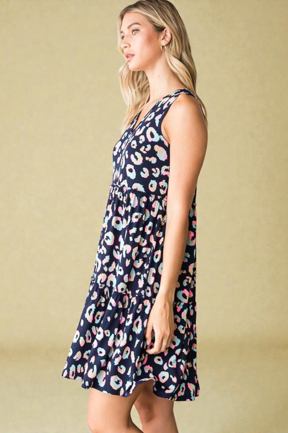 Woman wearing a navy dress with colorful floral pattern against a beige background