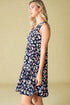 Woman wearing a navy dress with colorful floral pattern against a beige background