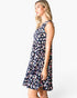 A woman modeling a sleeveless V-neck A-line dress with a navy blue base and a colorful abstract floral print in pink, white, and light blue, set against a plain white studio background.