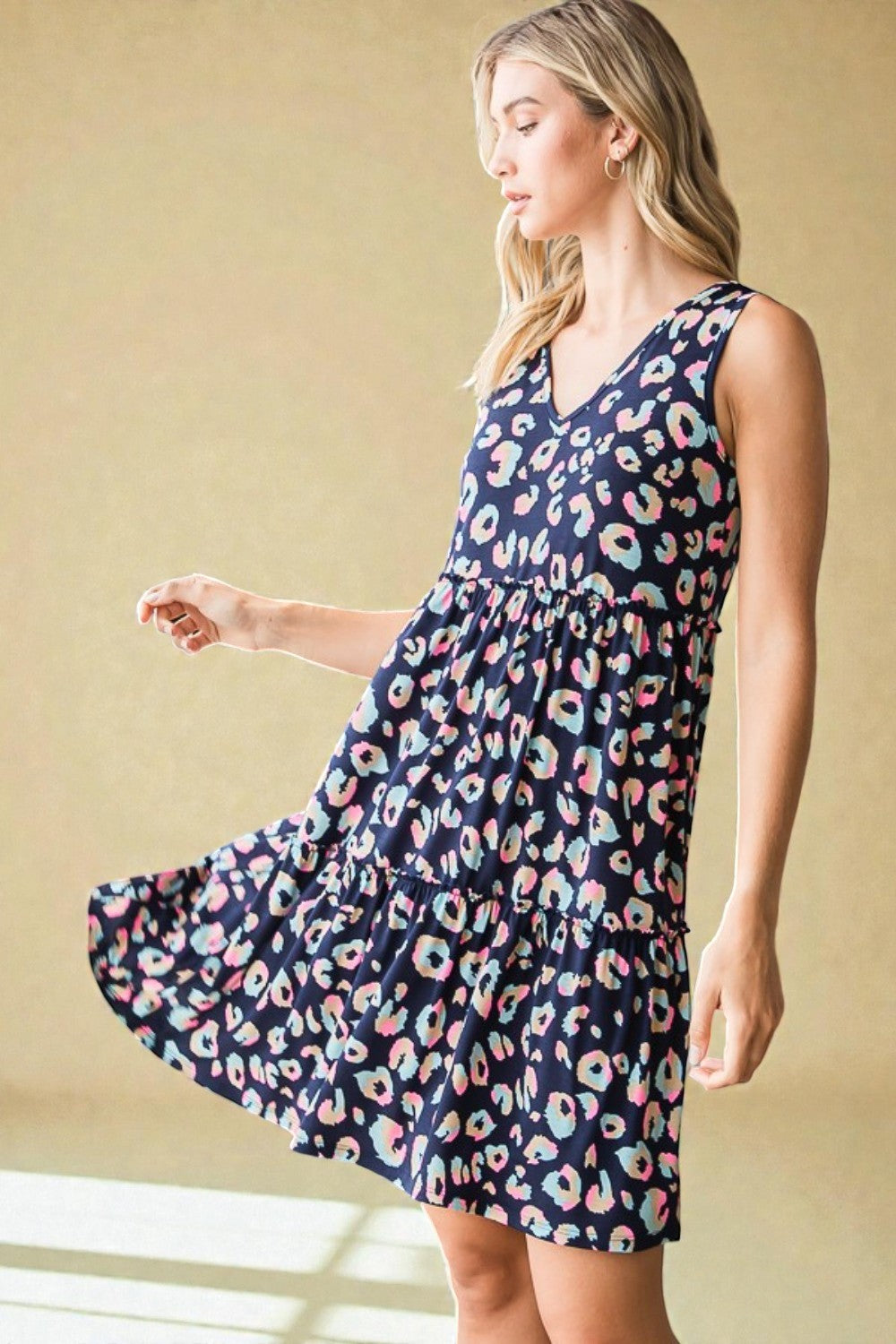 Woman wearing a navy dress with colorful floral pattern against a beige background
