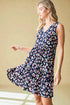 Woman wearing a navy dress with colorful floral pattern against a beige background