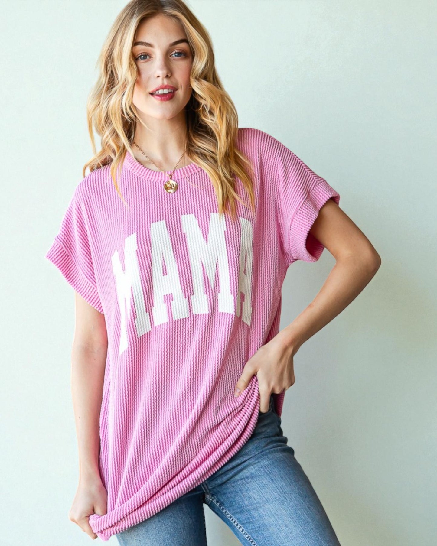 Woman wearing a pink 'MAMA' t-shirt against a light background