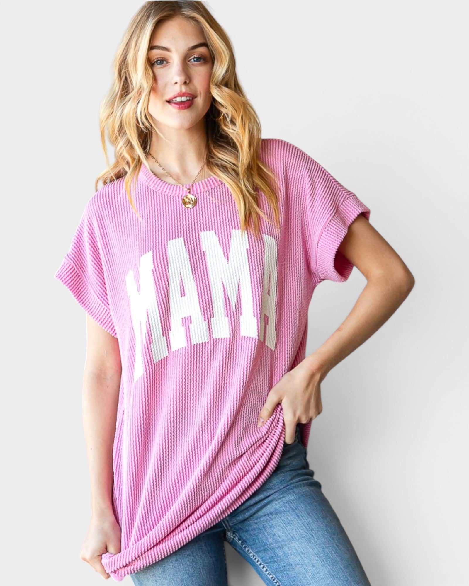 Woman wearing a pink oversized t-shirt with 'MAMA' printed on it against a plain background