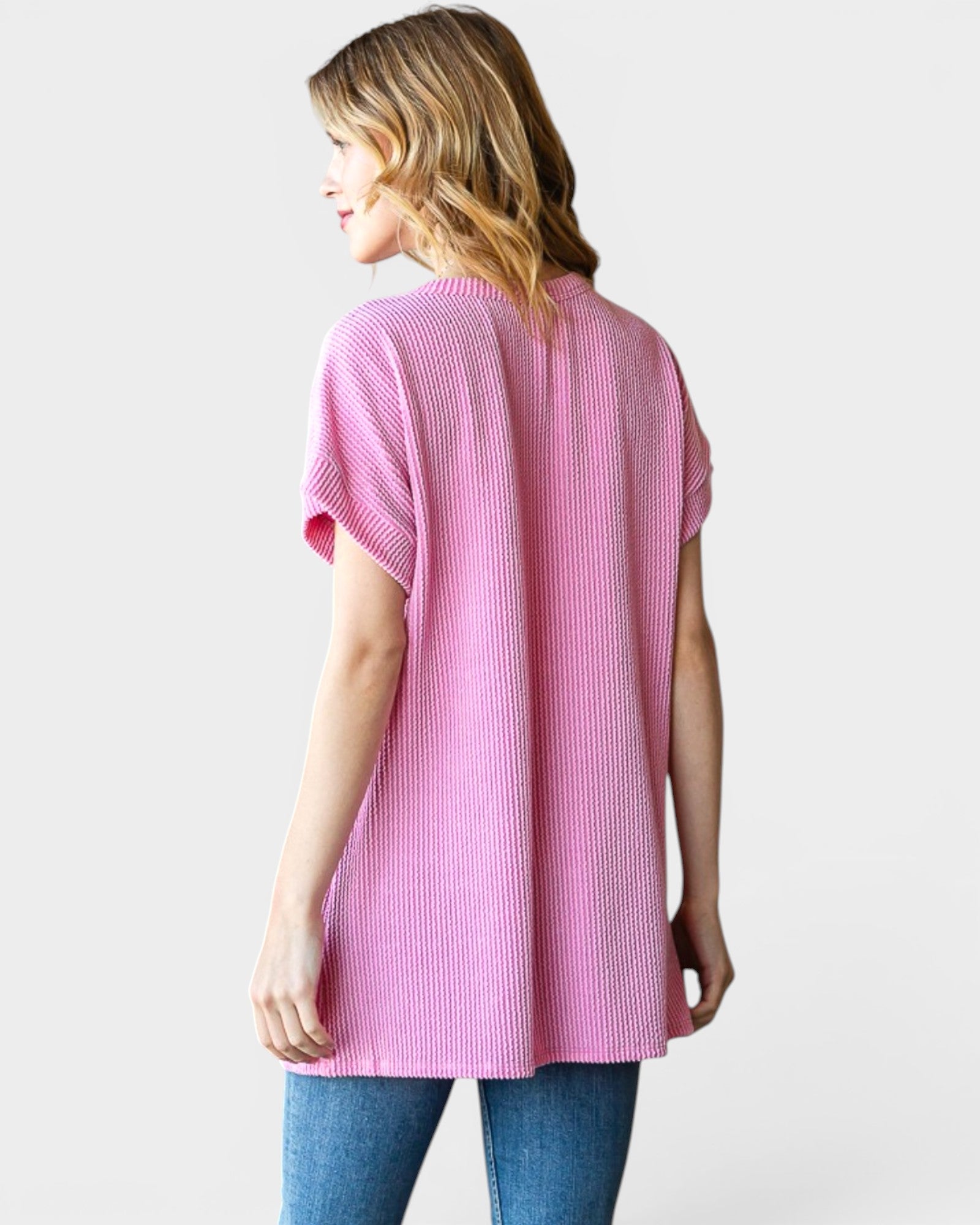 Woman wearing a pink ribbed sweater on a white background