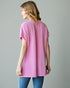 Woman wearing a pink ribbed sweater against a gray background