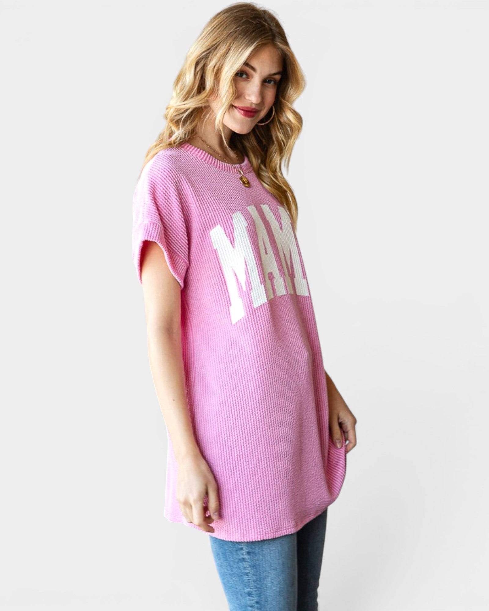 Woman wearing a pink oversized t-shirt with 'MAMA' text on a plain background