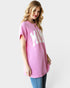 Woman wearing a pink oversized t-shirt with 'MAMA' text on a plain background