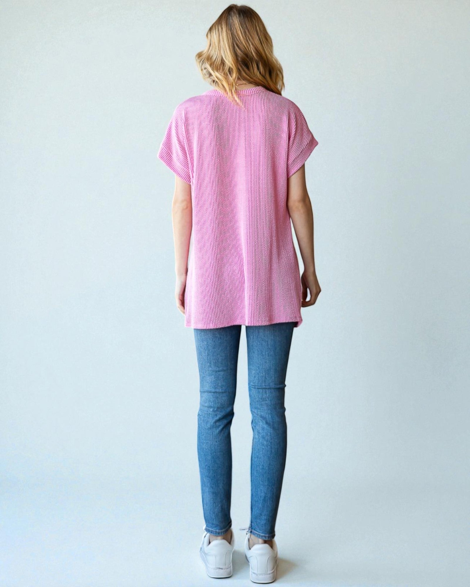 Person wearing a pink t-shirt and blue jeans on a white background