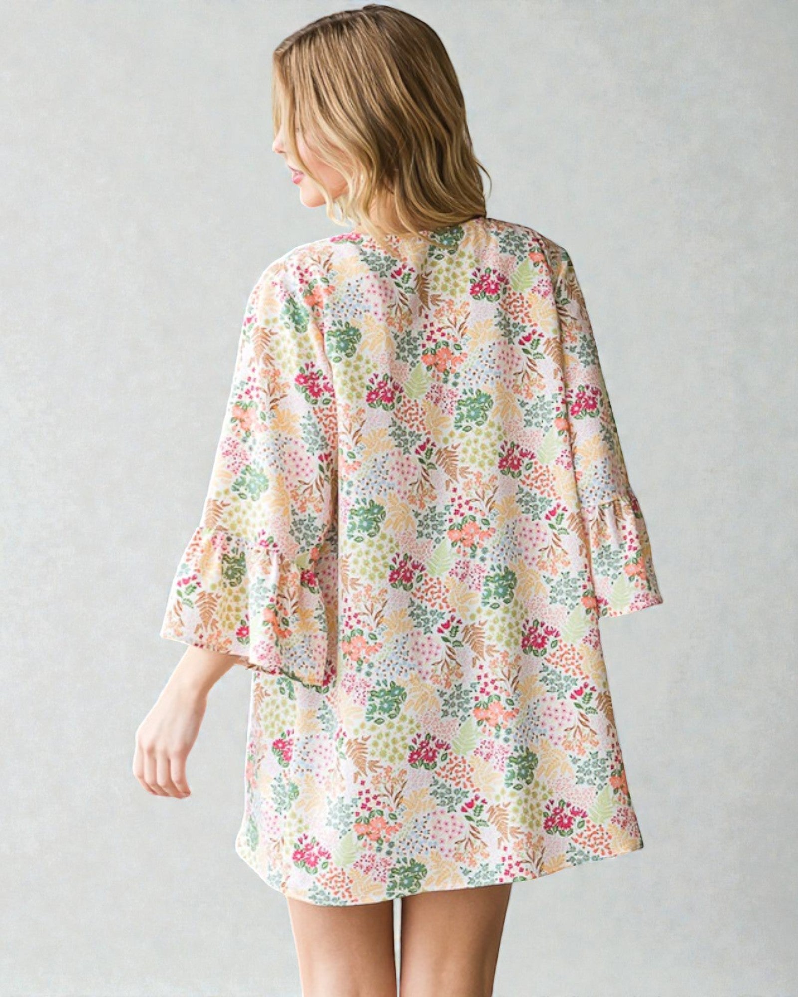 Woman wearing a floral kimono-style garment against a plain background