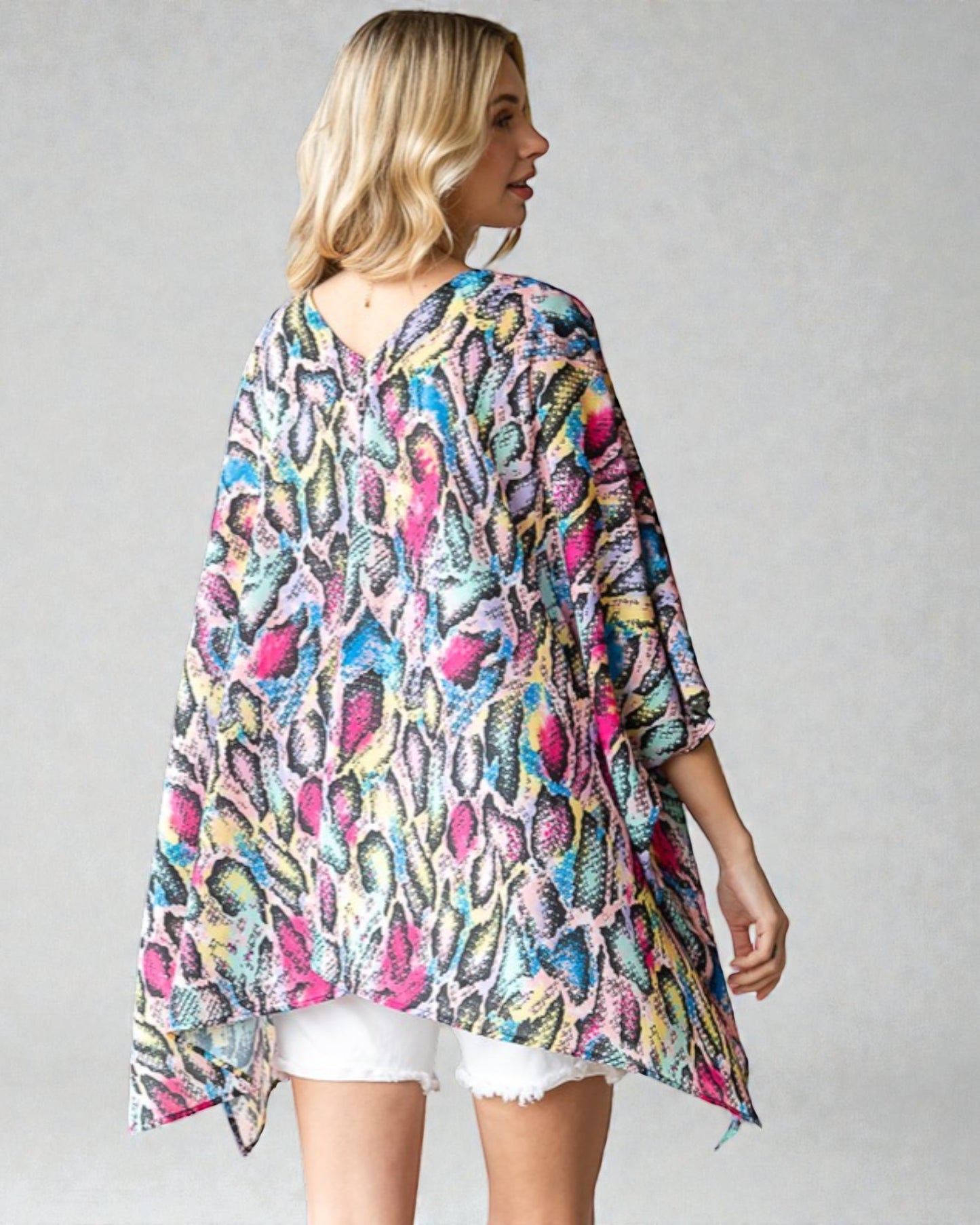 Woman wearing a colorful patterned kimono-style garment on a plain background