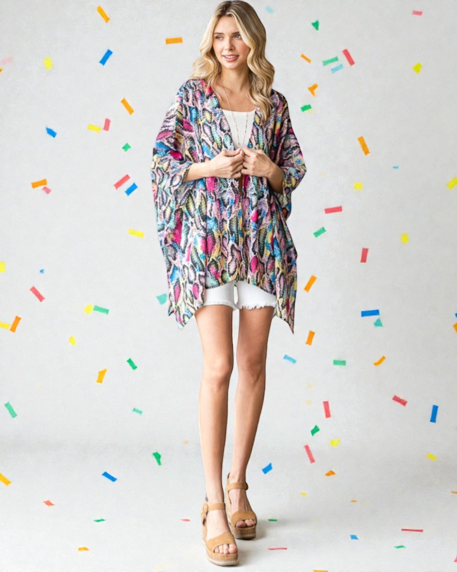 Woman wearing a colorful kimono-style garment against a light gray background with colorful confetti-like shapes.