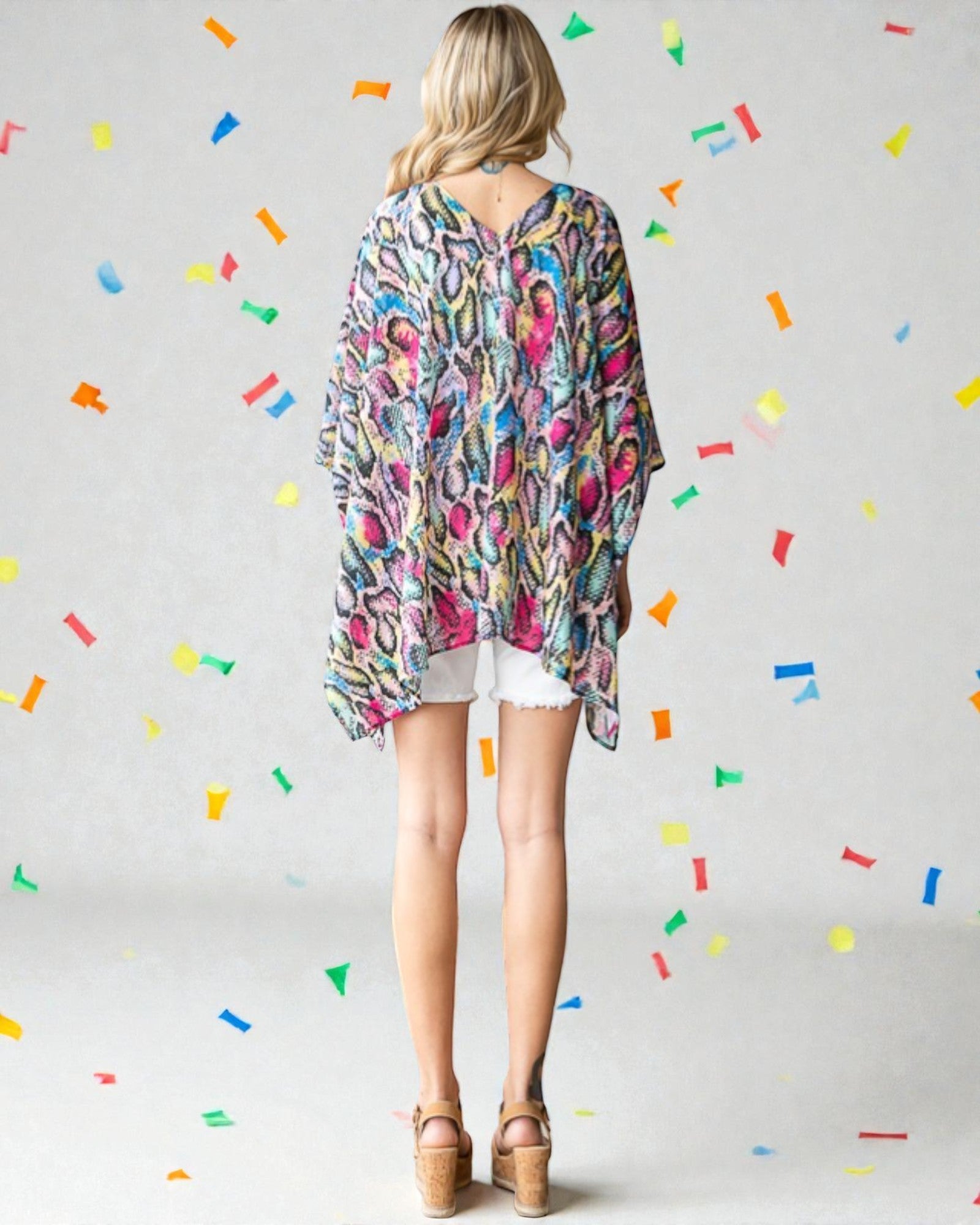 Woman wearing a colorful patterned shirt with a plain background and colorful confetti-like shapes.
