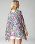 Woman wearing a colorful patterned kimono-style garment on a plain background