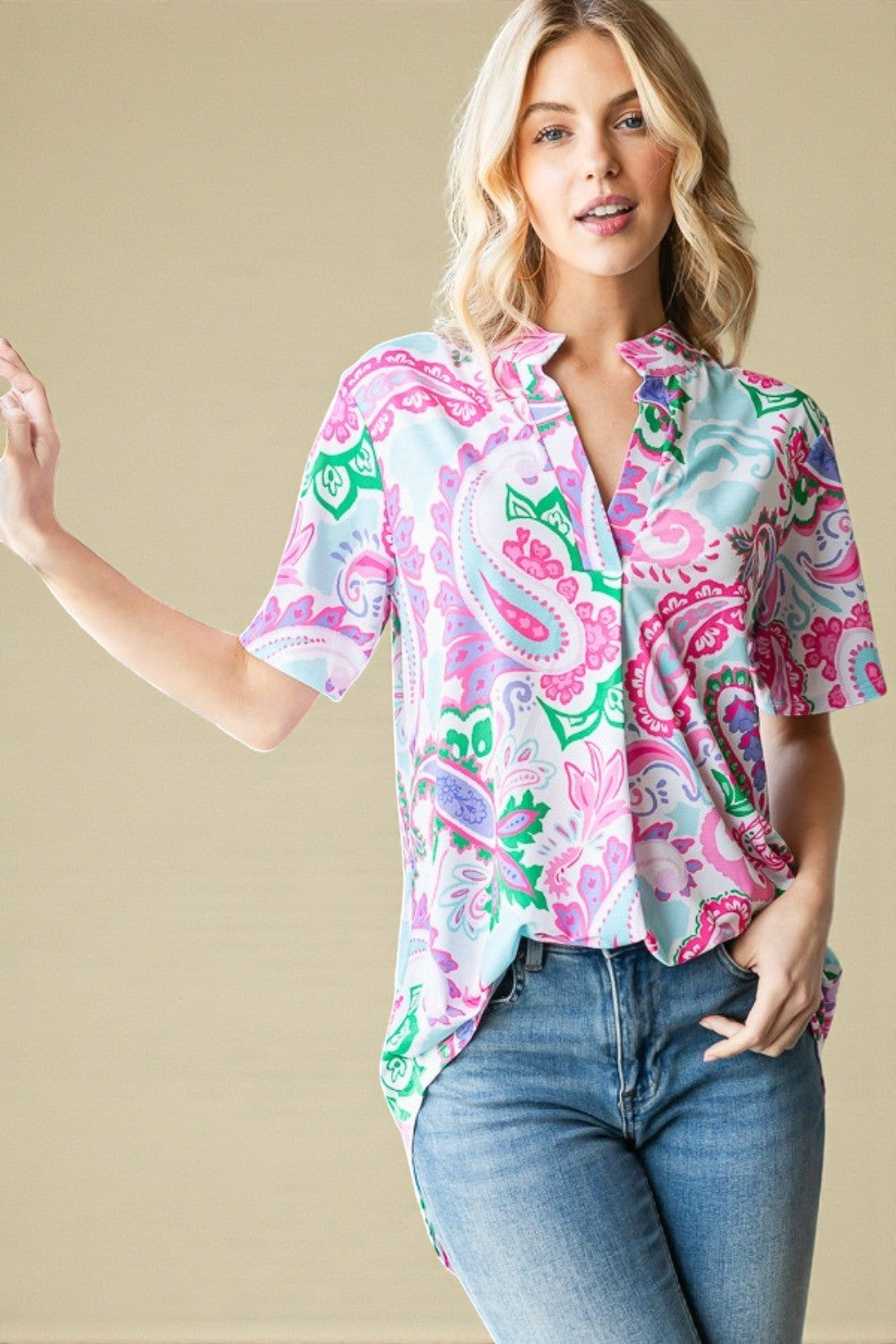 Woman wearing a colorful patterned shirt and jeans against a beige background