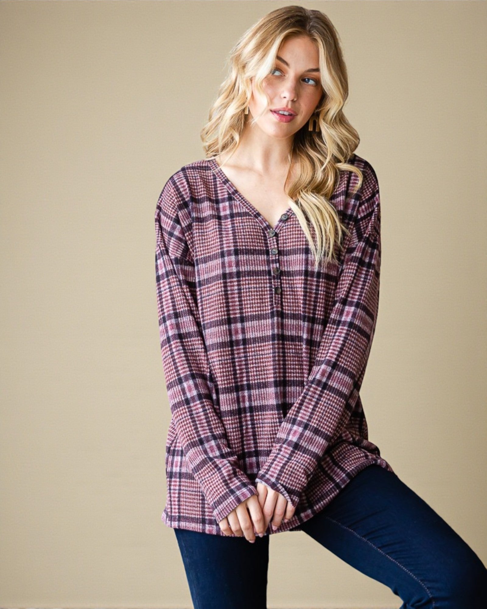 Woman wearing a plaid long-sleeve shirt against a beige background