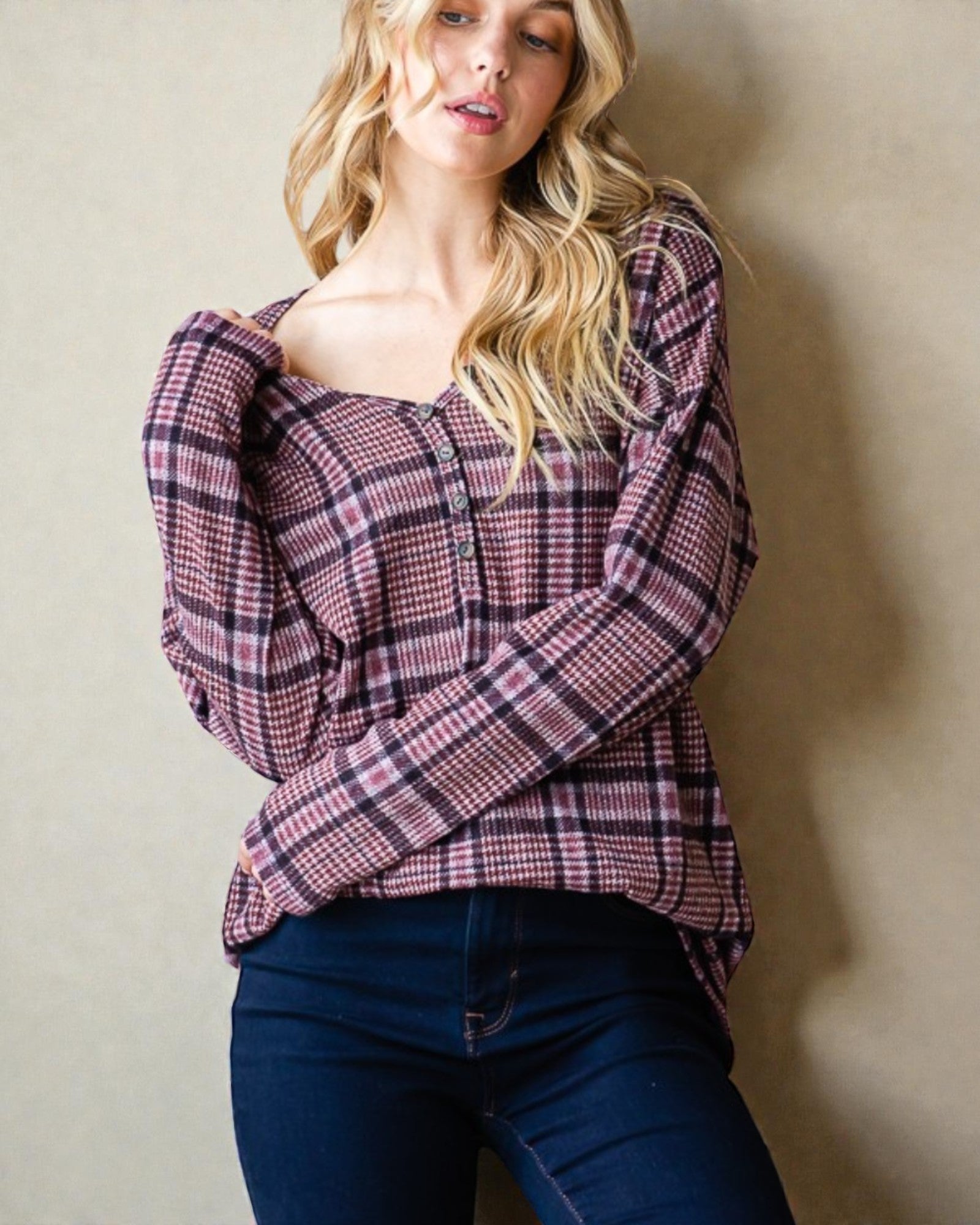 Woman wearing a plaid shirt and blue jeans against a plain background