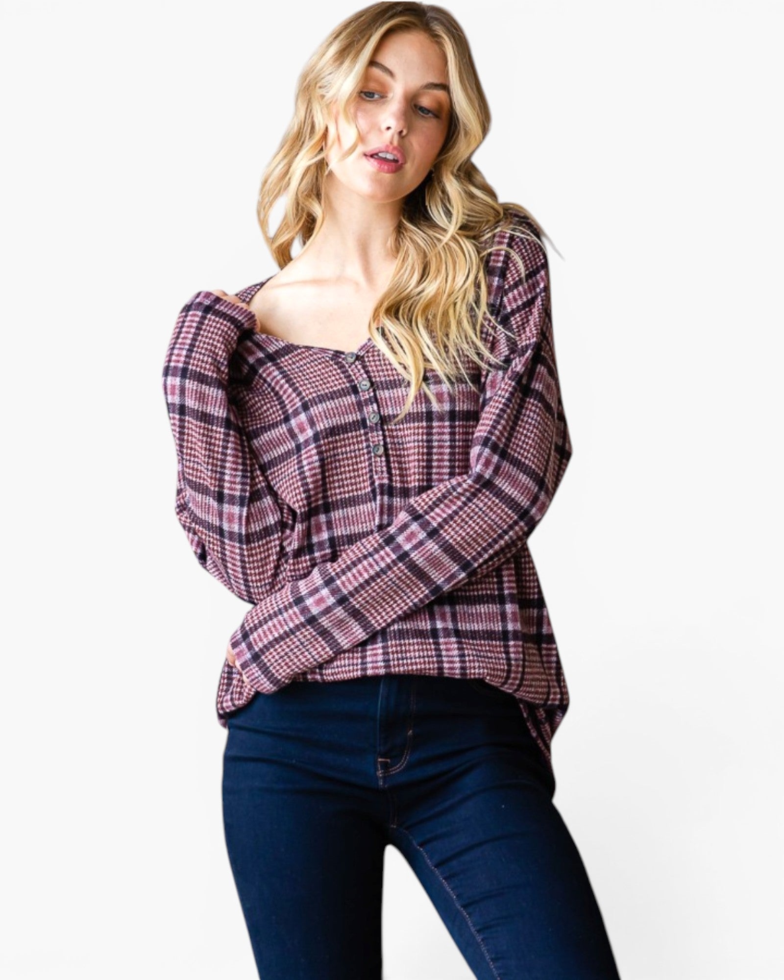 A woman modeling a long-sleeve plaid top with a square neckline and dark blue jeans, photographed against a plain white studio background.