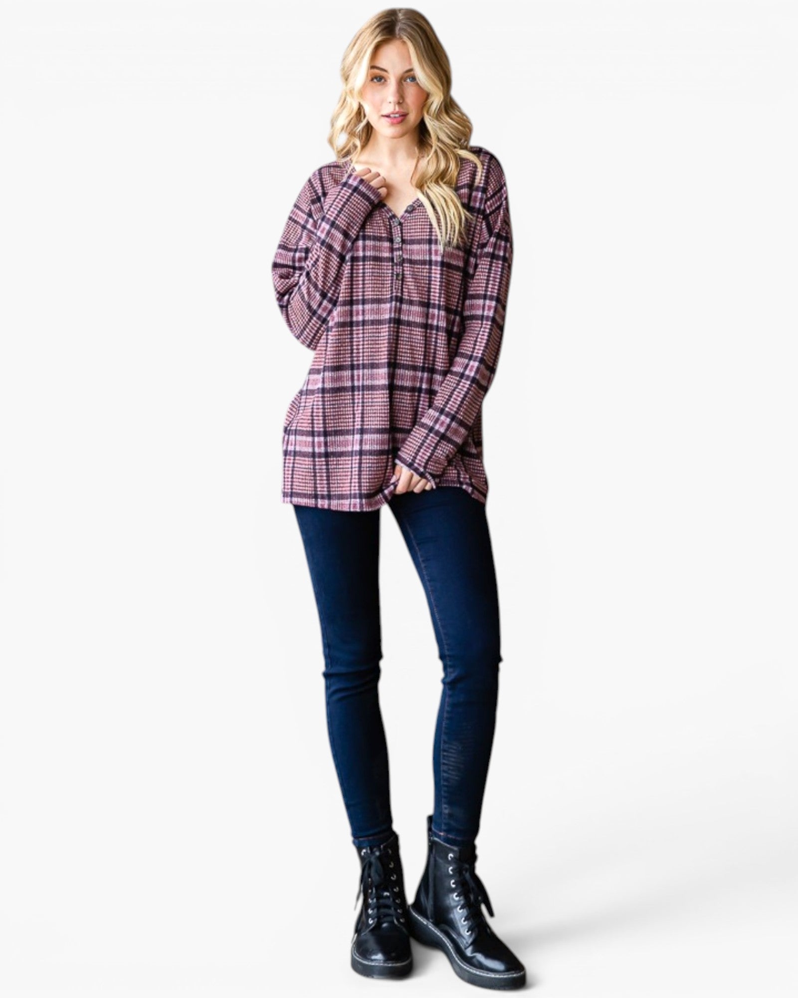 A woman modeling a long-sleeve plaid button-up shirt in purple and pink tones, paired with dark blue skinny jeans and black lace-up ankle boots, against a plain white studio background.