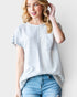Woman wearing a light gray t-shirt with a pocket and blue jeans on a white background