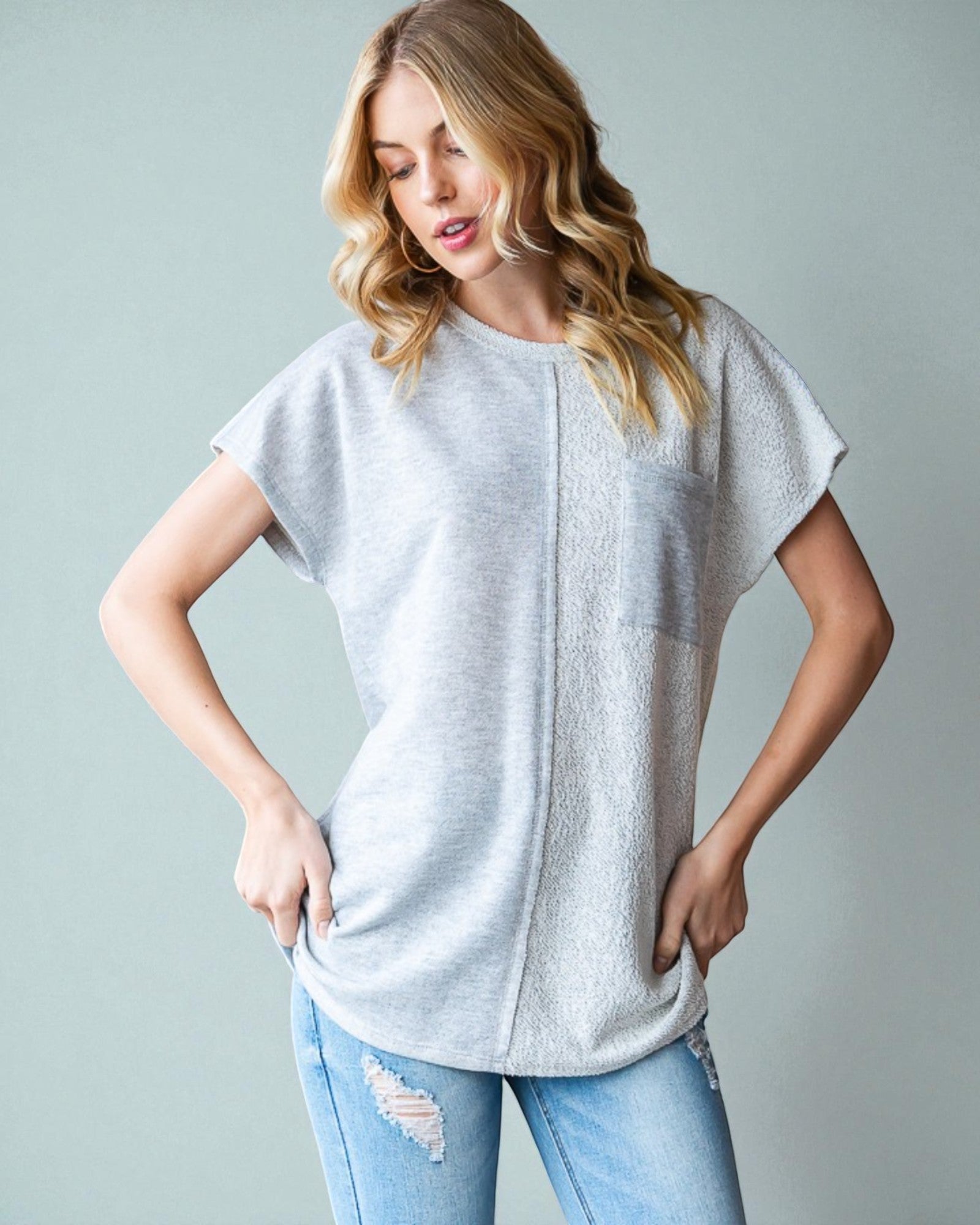 Woman wearing a light gray t-shirt and blue jeans against a plain background