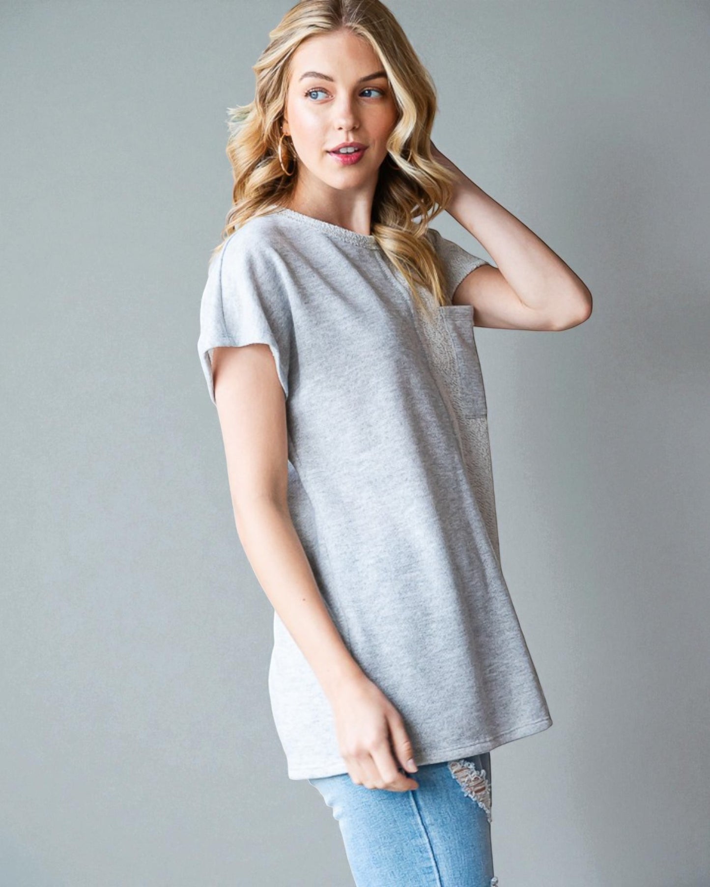 Woman wearing a gray oversized t-shirt against a plain background