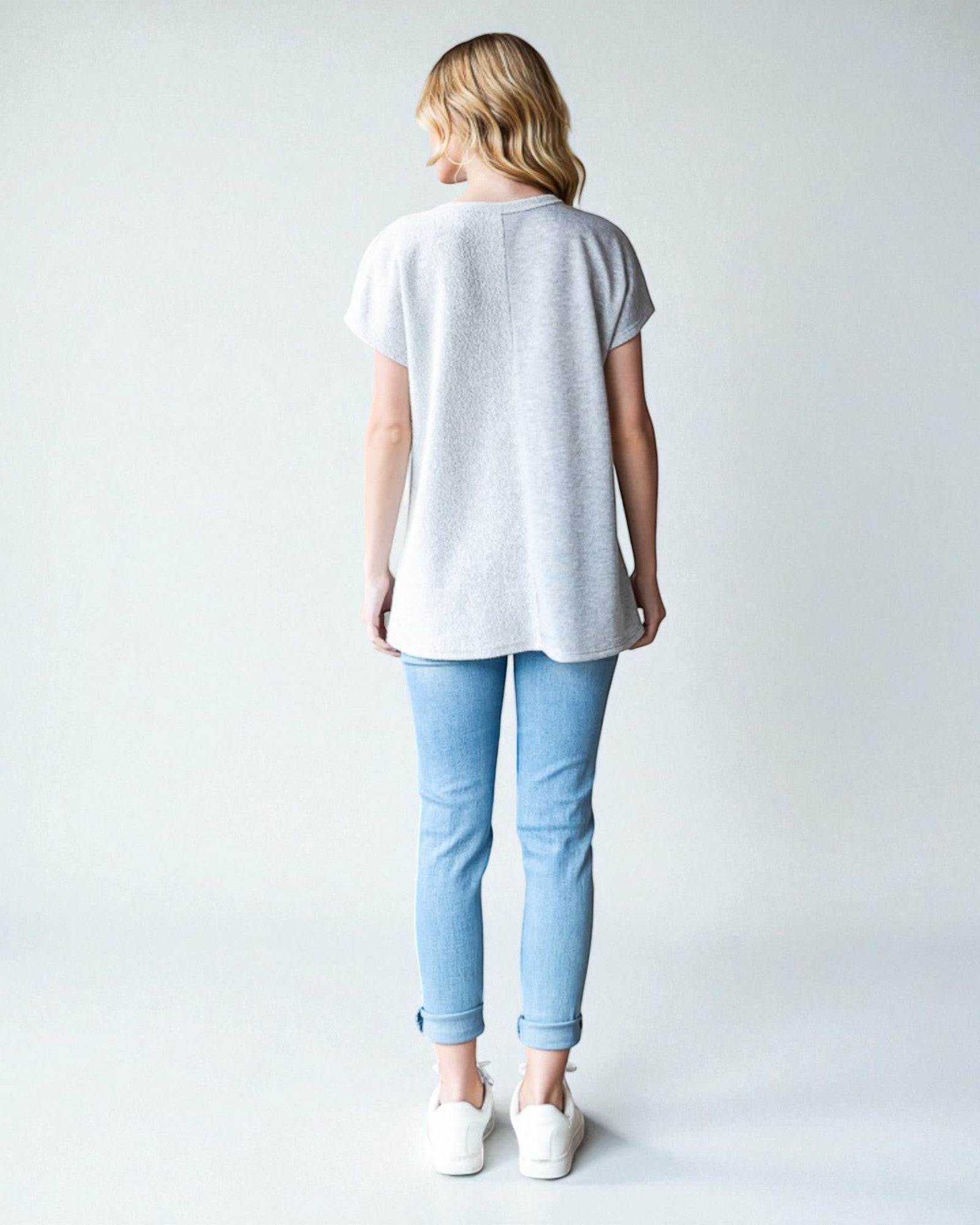 Person wearing a light gray t-shirt and light blue jeans on a white background