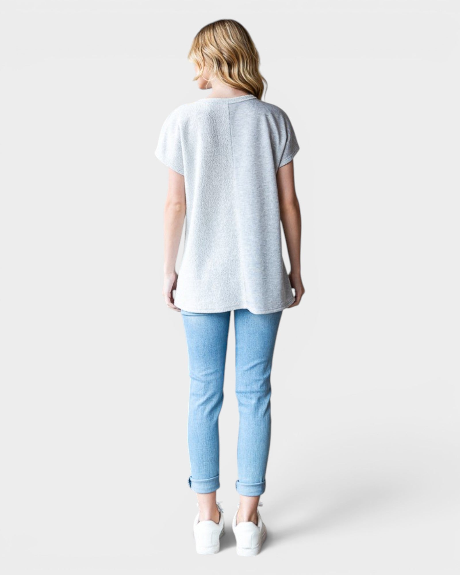 Person wearing a light gray t-shirt and blue jeans on a white background