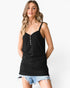 A woman modeling a black spaghetti-strap camisole top with a small button placket, paired with denim shorts, against a plain white background.