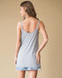 Woman wearing a light gray tank top and denim shorts on a beige background