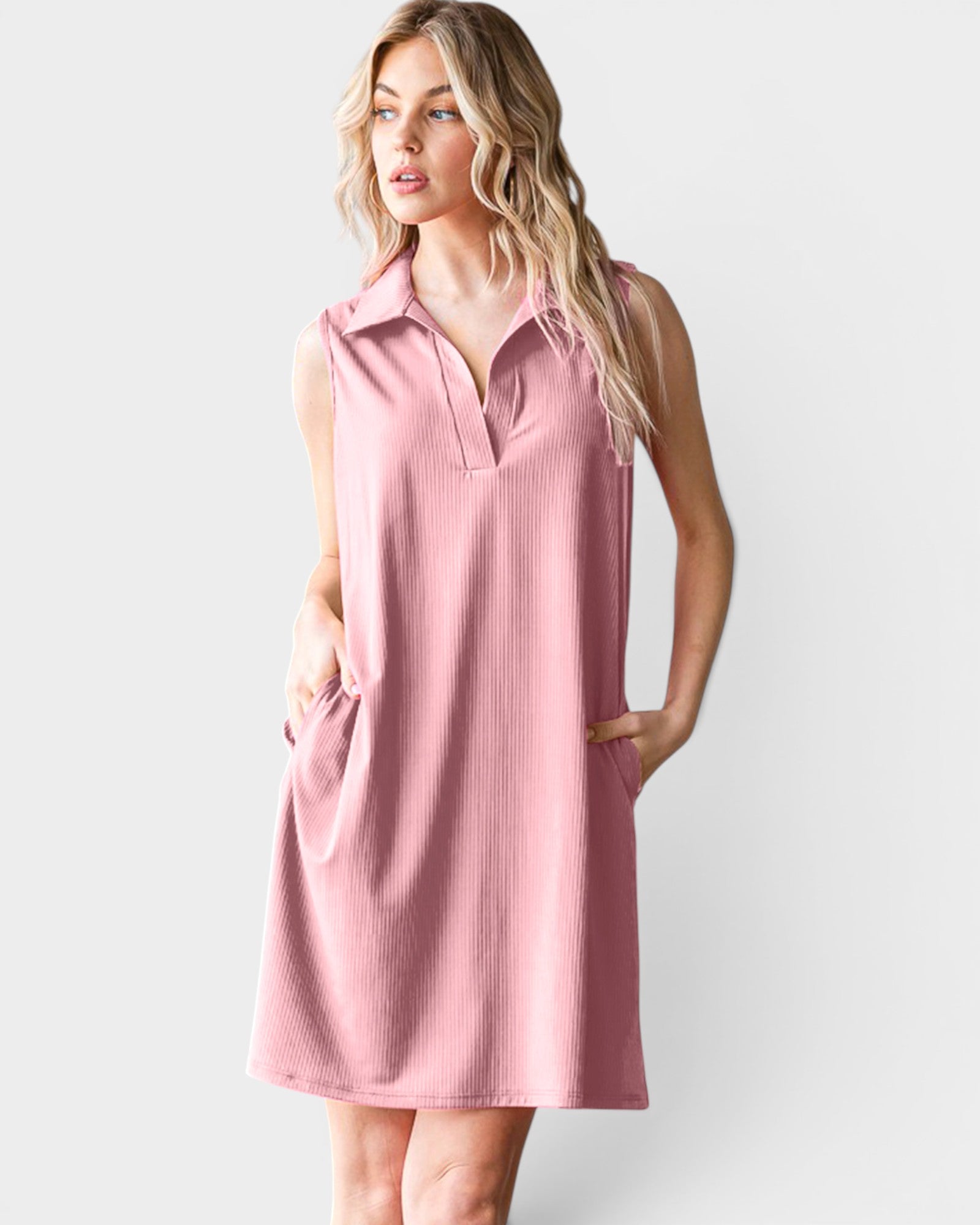 Woman wearing a pink sleeveless dress with a collar on a white background