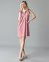Woman wearing a pink dress against a gray background