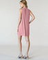 Woman wearing a pink sleeveless dress on a plain background