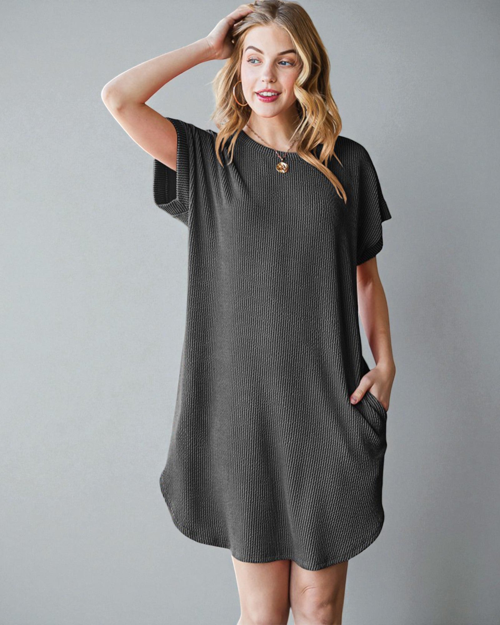 Woman wearing a dark gray dress with a button detail on a gray background