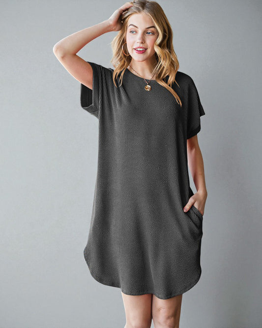 Woman wearing a dark gray dress with a button detail on a gray background