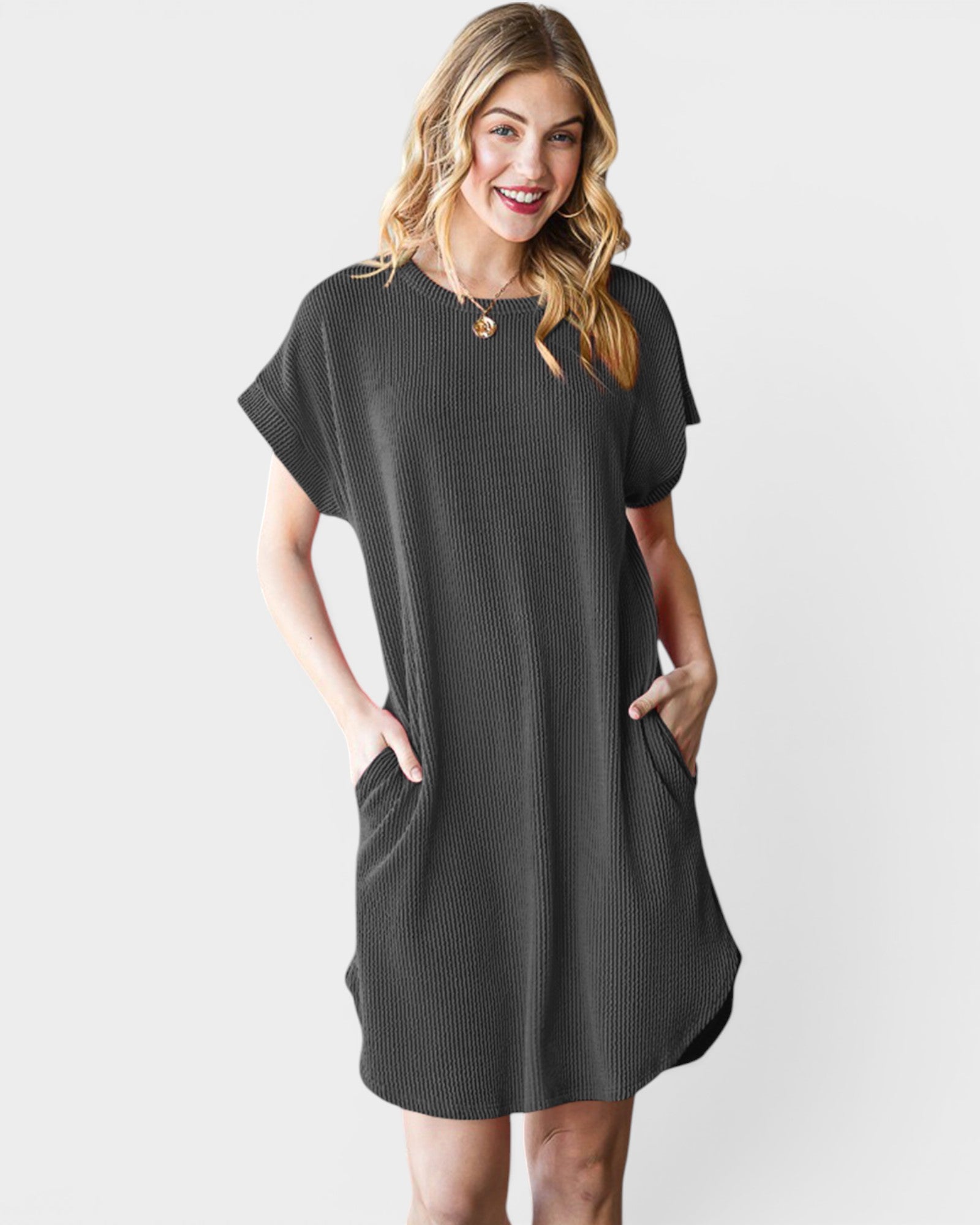 Woman wearing a dark gray dress with short sleeves and pockets on a light gray background