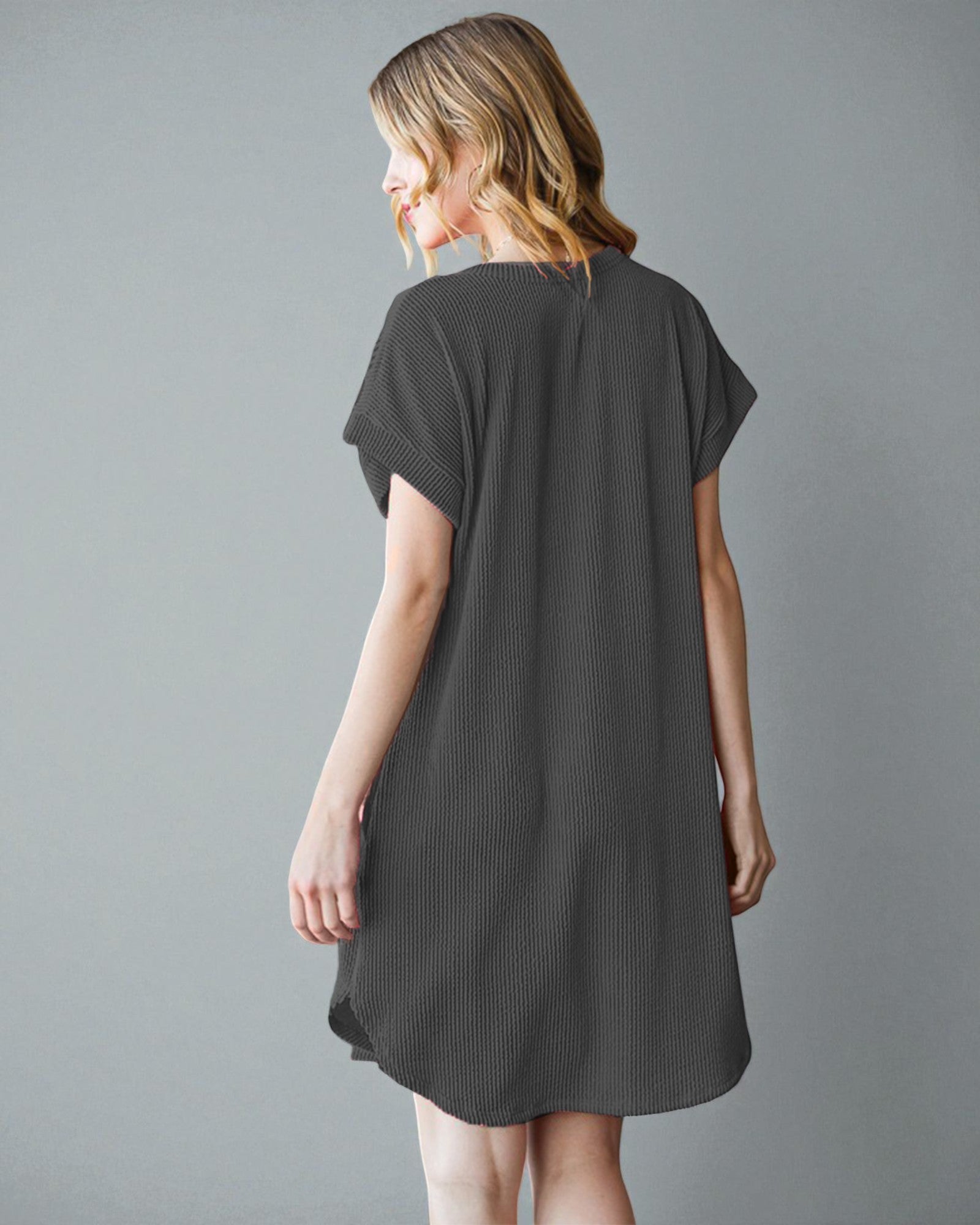 Woman wearing a dark gray t-shirt dress against a plain background